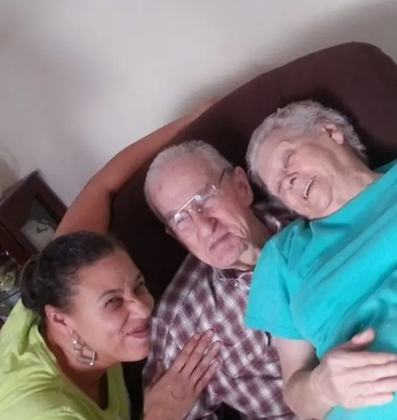 Nurse smiling with senior clients relaxing together on couch at home