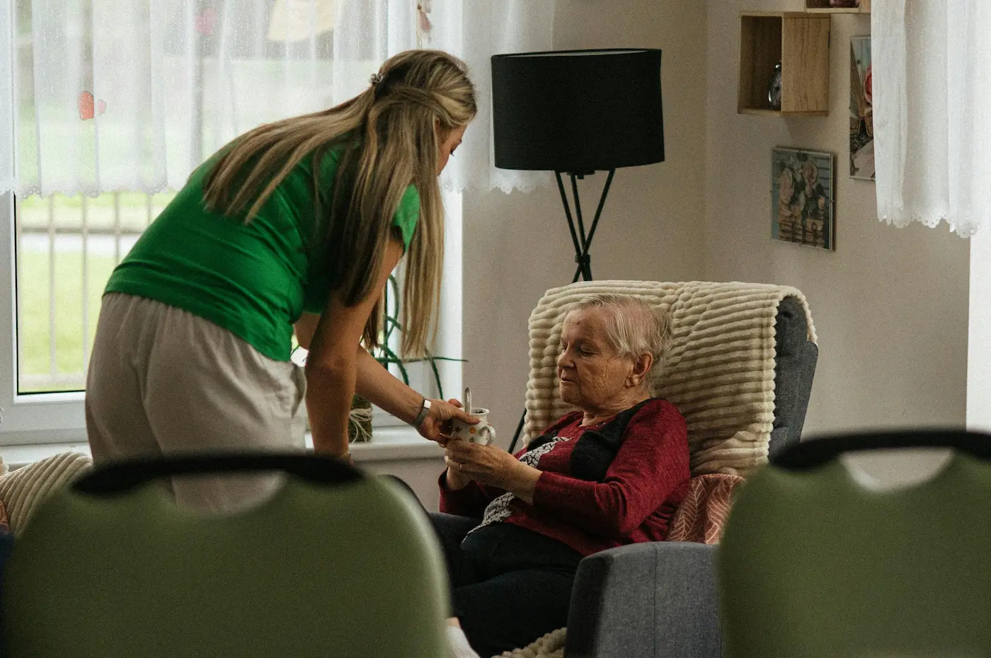 In-home nurse helping senior client with a drink